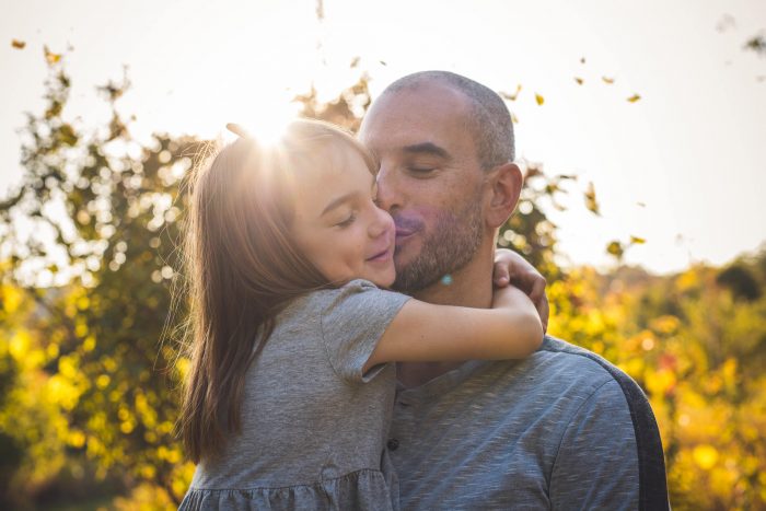 Father kissing daughter in sunlight